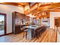 Expansive kitchen boasts wood-beamed ceilings, an oversized island with seating, and stainless steel appliances at 537 Moonstone Rd, Breckenridge, CO 80424