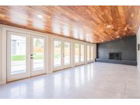 Bright sun room with fireplace, wood ceiling, tile floor, and glass doors to the backyard at 6935 W 16Th Ave, Lakewood, CO 80214