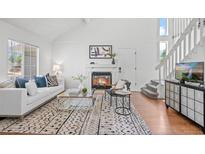 Bright living room features a fireplace, white sofa with patterned cushions, and wood floors at 1248 W 135Th Ave, Denver, CO 80234
