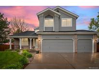 Charming two-story home boasts a three-car garage and manicured landscaping at sunset at 8533 S Flower Ct, Littleton, CO 80128