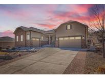 Charming two-story home with stone accents, a three-car garage, and a beautifully landscaped front yard at sunset at 3981 Old Oaks St, Castle Rock, CO 80104