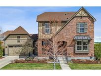 Charming two-story brick home with manicured lawn and a covered front entry, set against a blue sky at 2794 Lima St, Denver, CO 80238