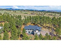 Beautiful aerial view of an elegant home surrounded by lush greenery and mountain views at 24701 Us Hwy 40, Golden, CO 80401