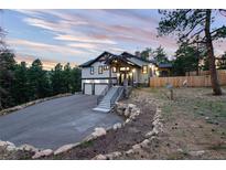 Beautiful home featuring a landscaped yard, two-car garage, stone stairway, and an exterior elevation with mountain views at 24701 Us Hwy 40, Golden, CO 80401