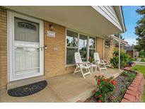 Inviting front porch features seating and charming brick accents, perfect for relaxing outdoors at 2121 W 73Rd Pl, Denver, CO 80221