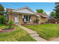 Charming brick home with a well-manicured lawn and inviting front porch seating area at 2121 W 73Rd Pl, Denver, CO 80221