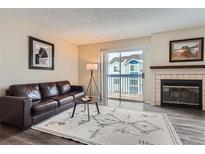 Living room with fireplace, balcony access, and hardwood floors at 1312 S Cathay Ct # 202, Aurora, CO 80017