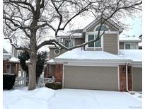 Two-story townhome with attached garage, snow-covered landscaping, and brick accents at 9866 Carmel Ct, Lone Tree, CO 80124