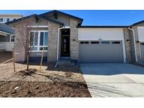 Charming single-Gathering home with a grey garage door, brick accents, and modern design elements at 6615 N Nepal St, Aurora, CO 80019