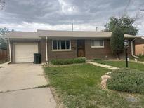 Charming brick home with a well-manicured lawn, lush landscaping, and a convenient attached garage at 12899 E Nevada Ave, Aurora, CO 80012