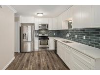 Modern kitchen features stainless steel appliances, white cabinets, and subway tile backsplash at 3460 S Poplar St # 404, Denver, CO 80224