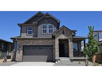 Beautiful two-story home featuring a stone and siding exterior, attached two-car garage, and covered porch at 6065 Caribou Dr, Brighton, CO 80601