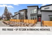 Modern two-story townhome with gray siding, wood fence, and landscaped walkway at 9445 W 58Th Cir # C, Arvada, CO 80002