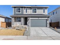 Charming two-story home with stone accents, gray siding, attached garage and freshly landscaped front yard at 270 Lark Sparrow Way, Bennett, CO 80102