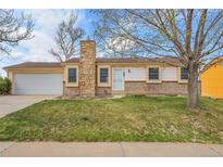 Charming single-story home with a stone chimney, well-manicured lawn, and a two-car garage at 11203 W Dorado Ave, Littleton, CO 80127