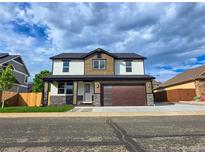 Two-story home featuring stone accents, a modern garage door, and a well-manicured lawn at 5550 Wetlands Dr, Longmont, CO 80504