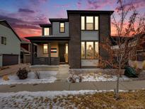 Modern two-story home boasts a covered front porch and a mix of siding and brick, complemented by snow-dusted landscaping at 9694 Meeker St, Littleton, CO 80125