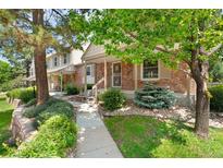 Charming brick home featuring a covered porch, beautiful landscaping, and mature trees in a desirable neighborhood at 6929 E Briarwood Dr, Centennial, CO 80112