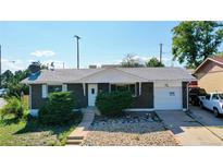 Brick ranch home with attached garage, landscaping, and a spacious driveway at 7609 Sherman Pl, Denver, CO 80221