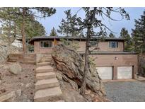 Charming exterior of a multi-level home with stone accents, stairs, and a two-car garage at 27857 Apex Cir, Evergreen, CO 80439