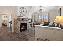 Bright living room featuring a stone fireplace, wood floors, and comfortable seating at 12762 Ironstone Way # 302, Parker, CO 80134