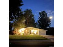 Charming single-story home with well-lit front yard and mature trees under a moonlit evening sky at 1360 S Hudson St, Denver, CO 80222