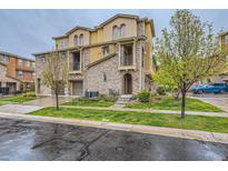 Attractive multi-story townhouse featuring stone accents, private balconies, and a well-maintained lawn at 9470 Loggia St # D, Highlands Ranch, CO 80126