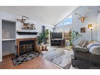 Cozy living room featuring a brick fireplace, vaulted ceilings, and abundant natural light at 4086 S Carson St # F, Aurora, CO 80014