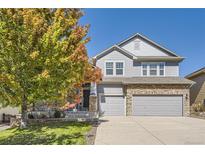 Charming two-story home with stone accents, a well-manicured lawn, and a beautiful tree at 23029 Cleveland Dr, Parker, CO 80138