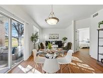 Open-concept dining area with modern lighting, a glass table, and views of the living room and outside patio at 12924 Ironstone Way # 103, Parker, CO 80134