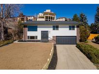 Charming two-story home featuring a two-car garage and a freshly landscaped front yard on a sunny day at 1411 S Welch Cir, Lakewood, CO 80228
