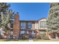 Inviting townhouse featuring a brick facade, chimney, and manicured landscaping at 3855 S Monaco St # 209, Denver, CO 80237