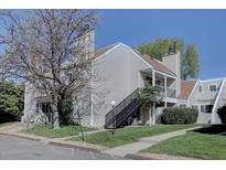 Inviting multi-story exterior with a black staircase, tan siding, and well-manicured lawn and landscape at 13633 E Yale Ave # B, Aurora, CO 80015