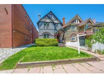 Charming two-story home featuring a well-manicured lawn and classic architectural details under a clear, sunny sky at 1365 Clayton St, Denver, CO 80206