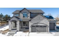 Two-story house with gray siding, stone accents, and a three-car garage at 3387 S Newcombe St, Lakewood, CO 80227