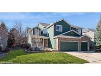 Inviting two-story home showcasing green siding, brick accents, and a well-maintained lawn and landscaping at 2829 S Fig St, Lakewood, CO 80228