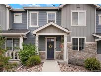 Charming townhome featuring a covered entryway with a wreath-adorned door and stone accents at 16461 E 119Th Way # B, Commerce City, CO 80022