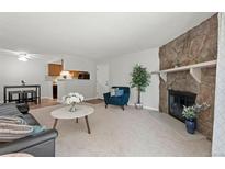 Inviting living room with stone fireplace, plush carpeting, and an open concept to the dining and kitchen area at 943 S Zeno Way # 102, Aurora, CO 80017
