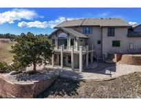 Beautiful home exterior with a large tree, stone landscaping, and a deck with arched windows, offering scenic views at 156 S Lookout Mountain Rd, Golden, CO 80401