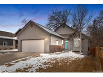 Charming single-Gathering home boasts a two-car garage and a pop of color with the bright teal front door at 3695 Quail St, Wheat Ridge, CO 80033