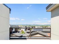 Balcony view overlooking rooftops with mountain views in the distance on a clear, sunny day at 22 Oneida Ct, Denver, CO 80230