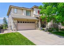 Charming two-story home with a stone-accented facade, large driveway and well-manicured lawn at 3211 Westbrook Ln, Highlands Ranch, CO 80129