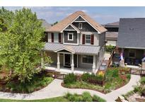 Charming home featuring gray siding, a covered front porch, and a beautifully landscaped front yard at 5080 Uinta St, Denver, CO 80238