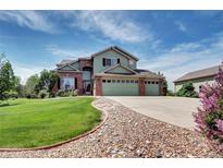 Two-story home with well-maintained lawn, three-car garage and manicured rock-lined driveway at 8720 E 163Rd Pl, Brighton, CO 80602