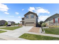 Charming two-story home features a well-manicured lawn, attached two car garage, and stone detailing at 603 Jewel St, Brighton, CO 80603
