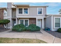 Charming townhome featuring a stone facade, a well-maintained front yard with lush greenery, and a welcoming entrance at 10321 E Evans Ave # 171, Aurora, CO 80247