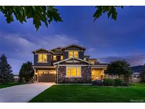 Beautiful two-story home at dusk featuring a well-manicured lawn, stone accents, and inviting curb appeal at 8661 Hunters Hill Ln, Littleton, CO 80125