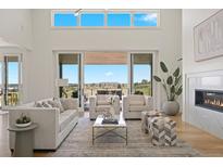 Spacious living room with high ceilings, fireplace, hardwood floors, and sliding glass doors to the backyard at 6176 Oxford Peak Ln, Castle Rock, CO 80108