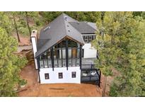 Striking two-story modern home with floor to ceiling windows and an inviting deck surrounded by lush green trees at 13910 Blue Jay Ln, Larkspur, CO 80118