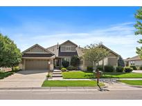 Charming single-Gathering home featuring a well-manicured lawn, stone accents, and an attached two-car garage at 22023 E Heritage Pkwy, Aurora, CO 80016